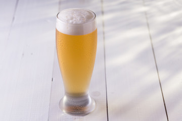 Tulipa de chopp gelado em mesa de madeira branca