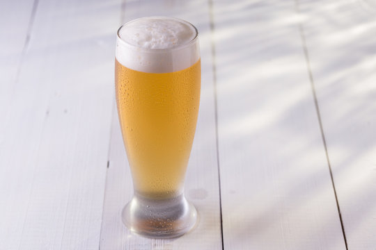 Tulipa de chopp gelado em mesa de madeira branca