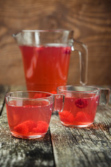 Berries compote in glass jar , two cup on wooden background. Selective focus.