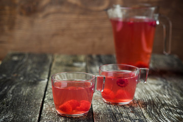 Berries compote in glass jar , two cup on wooden background. Selective focus.