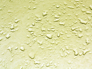 Water drops on yellow car metal surface.