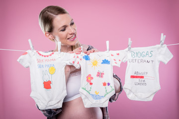 Schwangere Frau hängt Babywäsche auf