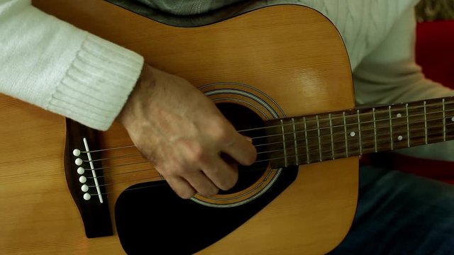 Man playing guitar close-up. Fingers playing on the strings of the guitar. A man with an acoustic guitar.