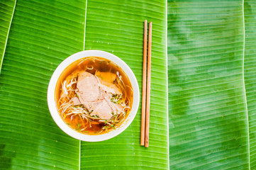 A bowl of Traditional Vietnamese beef soup Pho Bo on banana leaf background. © galitskaya