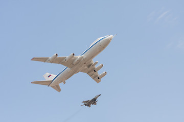  Il-80 command center for Russian officials and Mig-29 jet fighter fly against blue sky background
