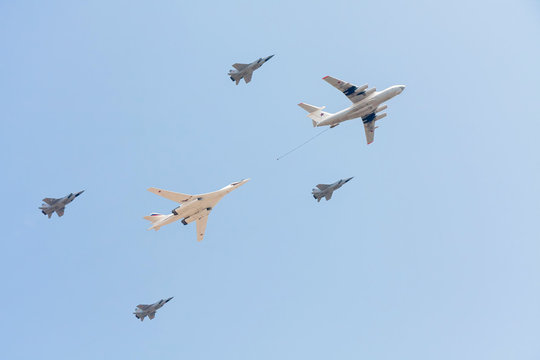 Il-78 refueling tanker with Tu-160 strategic bomber and Mig-31 supersonic interceptors fly against blue sky background
