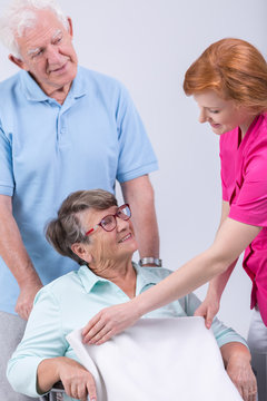 Caregiver helping woman on wheechair