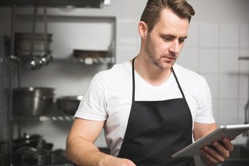 Handsome chef cooking meal holding tablet