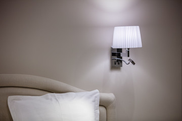 Cropped view of bedroom, part of bed and bracket wall light