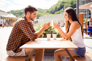 Two lovers having date in cafe and typing sms on smartphones