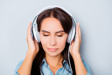 Portrait of calm woman listening music in headphones with closed