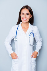 Fototapeta premium Cheerful friendly female doc holding hands in pockets of uniform