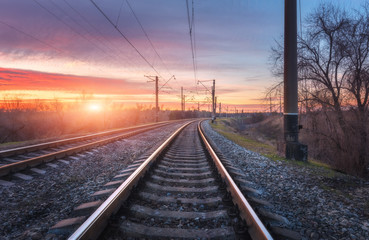 Fototapeta na wymiar Railroad against beautiful sunny sky. Industrial landscape with railway station, blue sky and colorful red clouds at sunset . Railway junction in the evening. Heavy industry. Cargo shipping. Travel