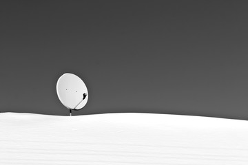 Sattelite antenna on snowy roof in black and white