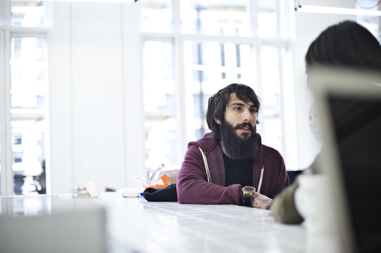 Caucasian male creative professional talking to colleagues in an informal studio work environment