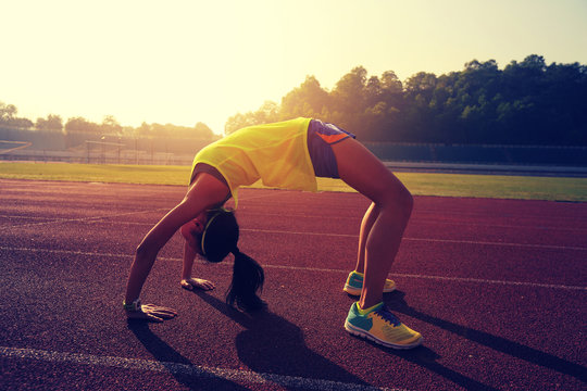 young asian woman backbending on stadium track