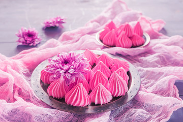  Air meringue with fresh flowers lie on a metal dish on a pink v