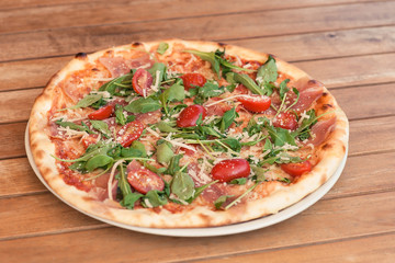 pizza on a wooden table with tomato and cheese