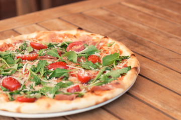 pizza on a wooden table with tomato and cheese