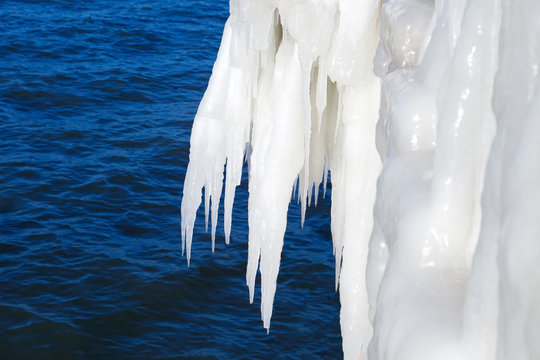 Large icicles on a background of the sea. Ice storm