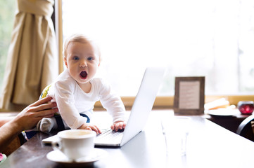 Unrecognizable man in cafe having coffee, holding his son
