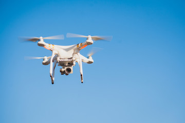 White quadrocopter flying high in the sky