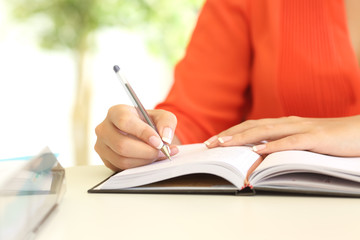 Businesswoman hand writing in agenda