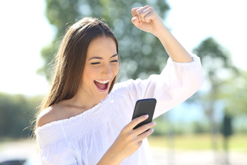 Excited girl with a mobile phone in a park