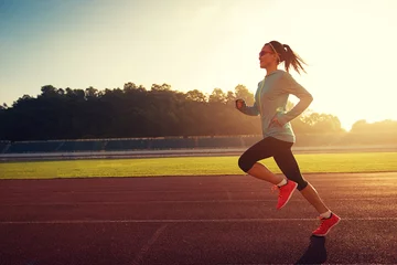 Photo sur Aluminium Jogging Young woman running during sunny morning on stadium track