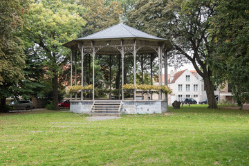 Fototapeta na wymiar öffentlicher Park mit einer Wiese und einem Musikpavillon zwisc
