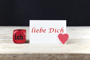 Valentine greeting card on wooden table with text " Ich liebe Dich", written in German, which means "I love you".