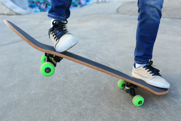 young skateboarder legs riding skateboard at skatepark