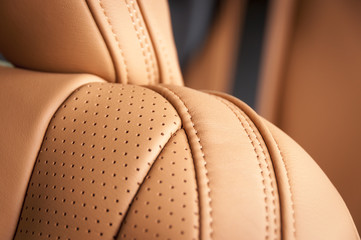 Part of red leather car seat with the unfocused car interior on the background