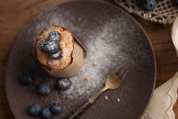 Blueberry muffin in a dish decorated with fresh blueberry and white candle on the table