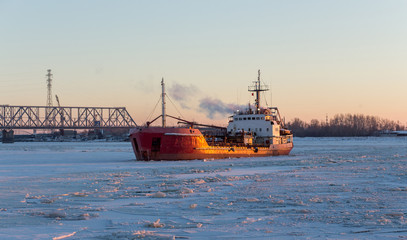 Ship tanker in the river ice. Frosty day