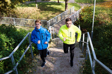 Two athletes running on stairs in sunny autumn nature.