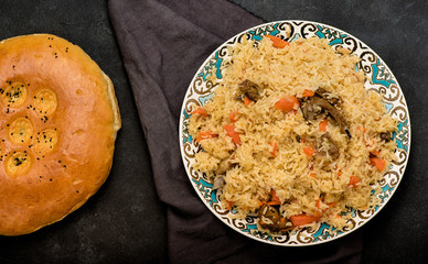 Pilaf on plate with oriental ornament and Traditional Asian breads - churek. Plov. Top view.