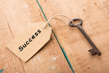 Old rusty key with a paper label on the wooden board