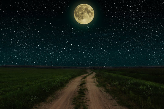 Beautiful magic night sky with fullmoon and stars  road receding into the distance  green grass