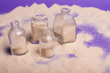 Obraz premium garrafas pequenas com areia em fundo roxo