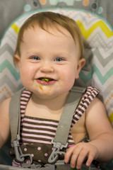 Baby girl acting goofy while eating green beans in her high chair