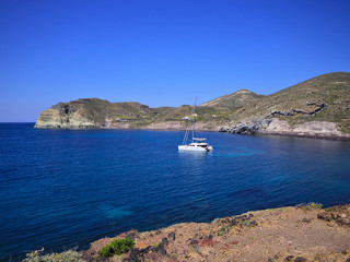 Catamaran sailing boat in small bay on blue sea. Santorini, Greece..