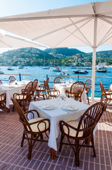 Dinner in a Spanish restaurant, Mediterranean sea resort. Cozy sidewalk cafe tables under umbrellas with sea view