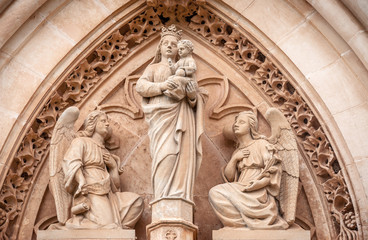 Obraz premium Sculpture of the Virgin Maria carrying a child surrounded by angels. Portal on the side-wall of Catedral de Santa Maria de Palma de Mallorca, one of the main sights of the Majorca island.