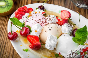 Banana split sundae ice cream in a bowl with strawberry and raspberry vanilla icecream scoops