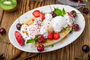 Banana split sundae ice cream in a bowl with strawberry and raspberry vanilla icecream scoops