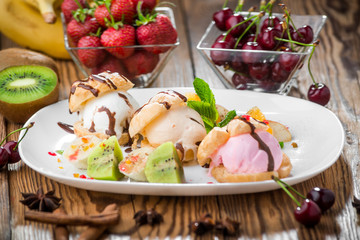 Banana split sundae ice cream in a bowl with strawberry and raspberry vanilla icecream scoops