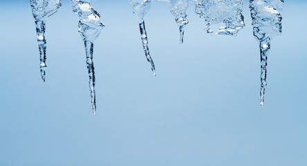 Naklejka na ściany i meble Ice transparent icicles hang on a clear winter day