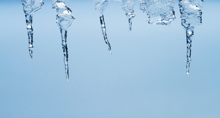 Obraz na płótnie Canvas Ice transparent icicles hang on a clear winter day