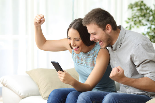 Excited couple watching media in a mobile phone